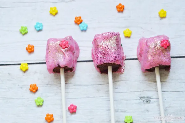 Whether you are planning a princess themed birthday party for girls or a tea party themed baby shower, these Princess Tea Party Glitter Brownie Pops are the ideal treat for your special event. Learn how to make these easy delicious decadent chocolate treats for your party! Click through for step by step instructions. Turn dessert into something magical!
