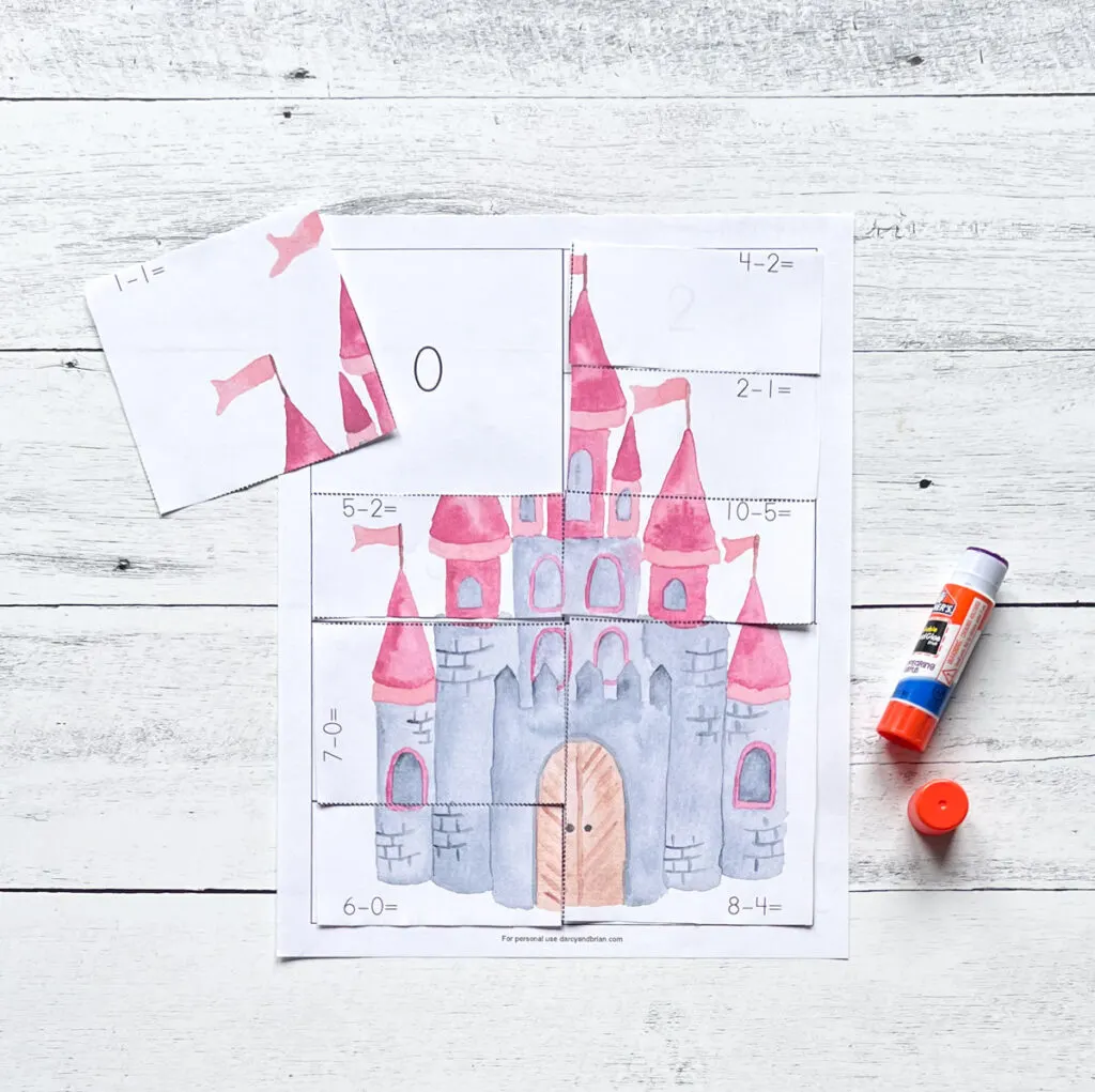 Picture of a watercolor castle with pink turret towers and flags being glued to the answer page.