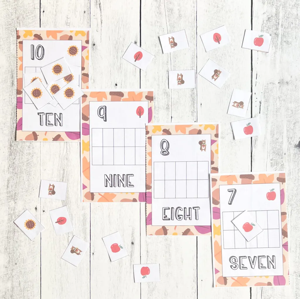 Four half sheets of paper with empty ten frames and numbers 10, 9, 8, and 7 with autumn themed borders. Small square pieces of paper are cut out and scattered around with pictures of fall objects.