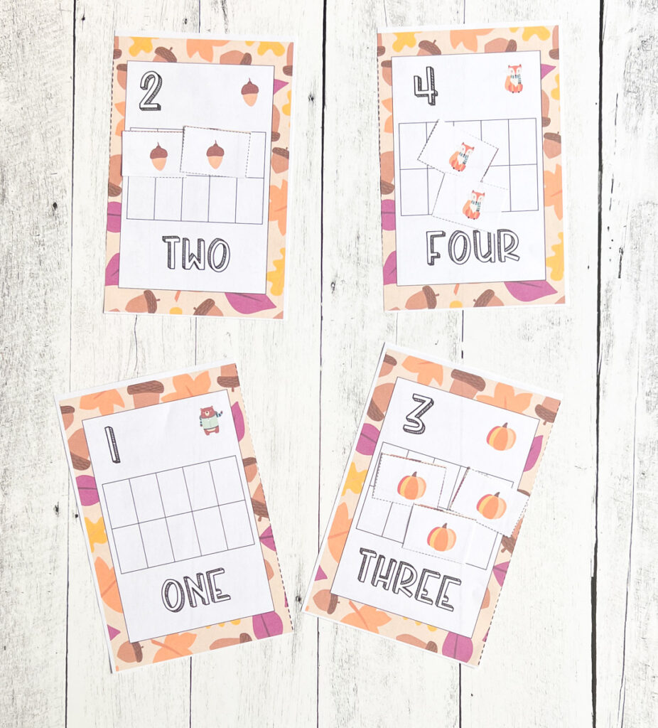 Four different counting task cards laying on white wood table featuring numbers 1, 2, 3, and 4. Fall themed tokens cover the corresponding number of spaces on the ten frames.