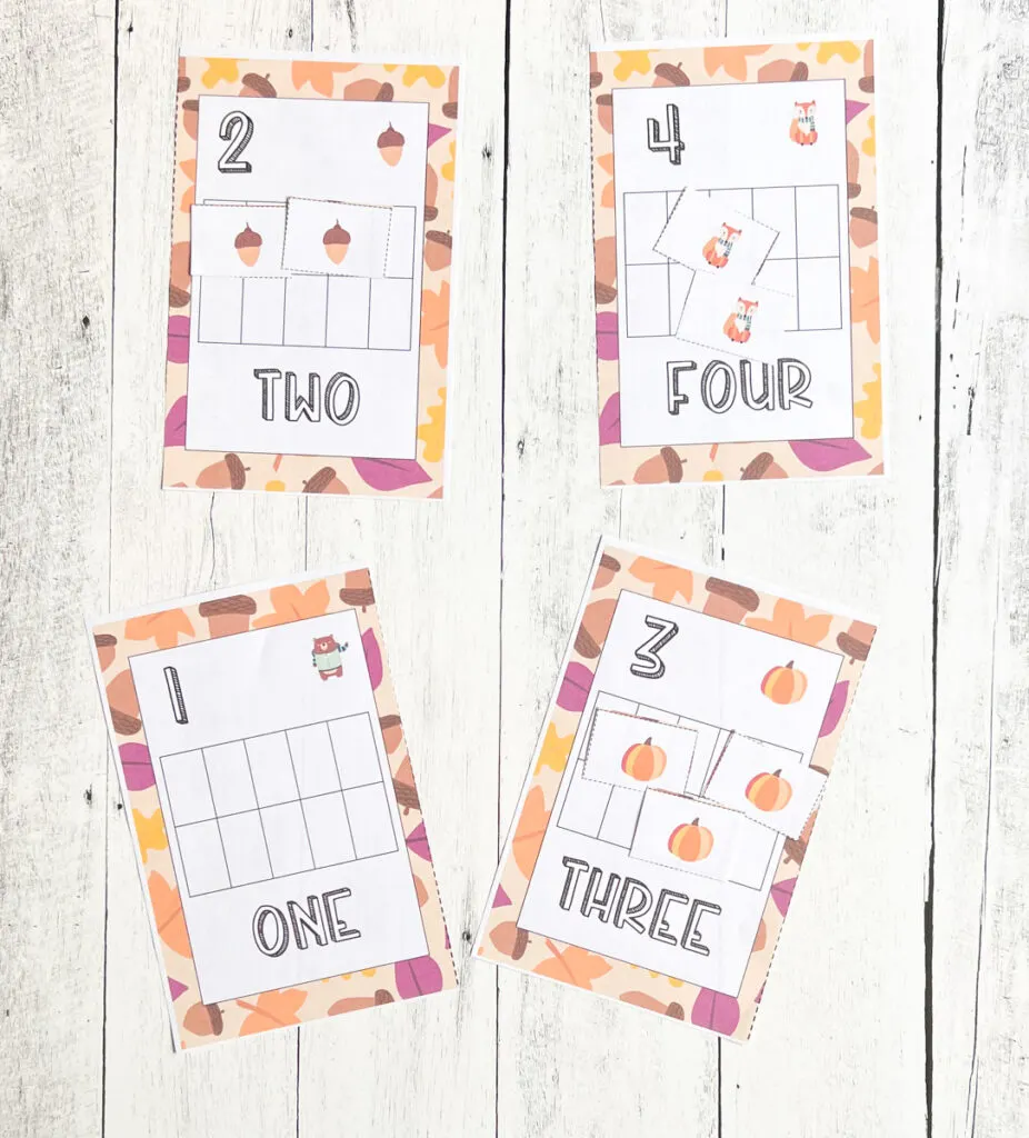 Four different counting task cards laying on white wood table featuring numbers 1, 2, 3, and 4. Fall themed tokens cover the corresponding number of spaces on the ten frames.