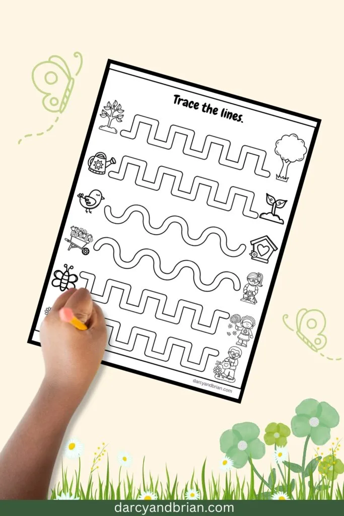 Empty line paths for drawing straight and curvy lines between cute black and white pictures. A child's left hand is holding a pencil over the bottom one.
