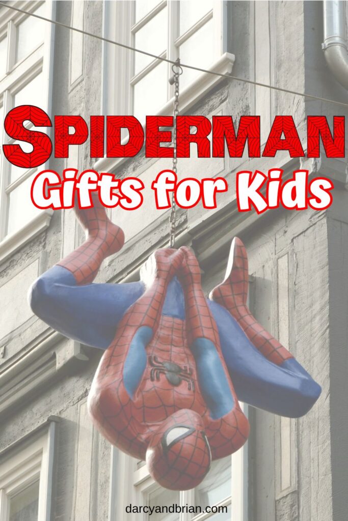 Red and white text says Spiderman Gifts for Kids. A large plastic Spiderman hanging from a chain in front of a building is the background.