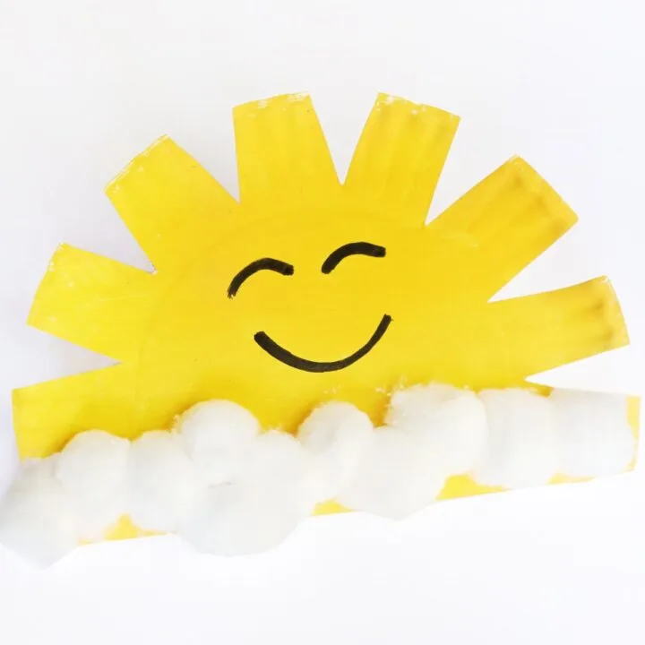 Plate painted yellow with cotton balls and a smiley face.