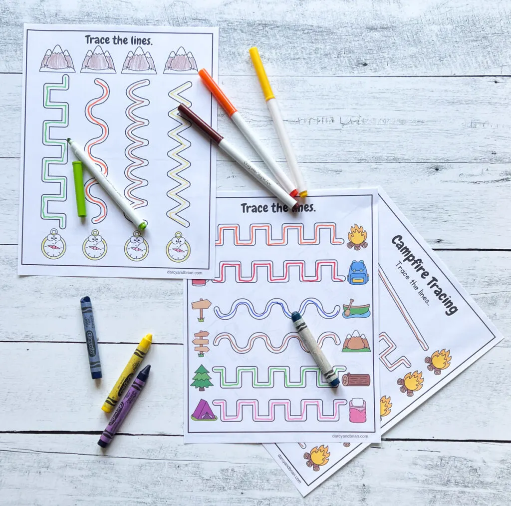 Markers in assorted colors spread out over line path worksheets with camp related pictures.