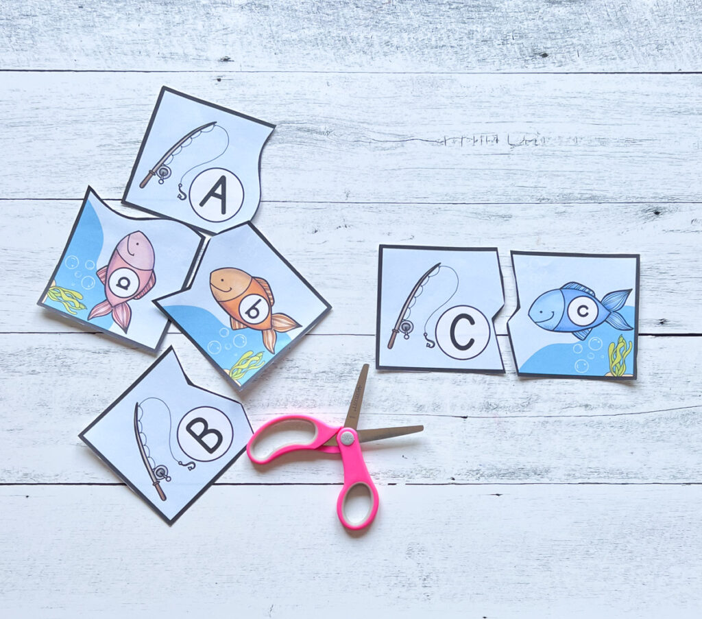 Assorted paper puzzle cards featuring fishing rods with capital letters and fish with lower case letters. The C and c are matched up.