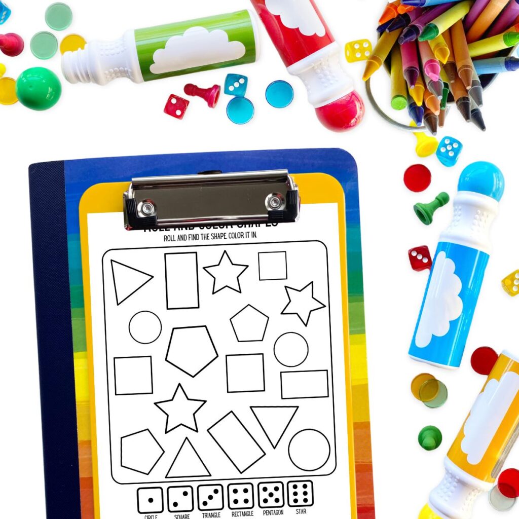 One roll and color shapes activity page on a clipboard next to assorted crayons, dot markers, dice, and game pieces.