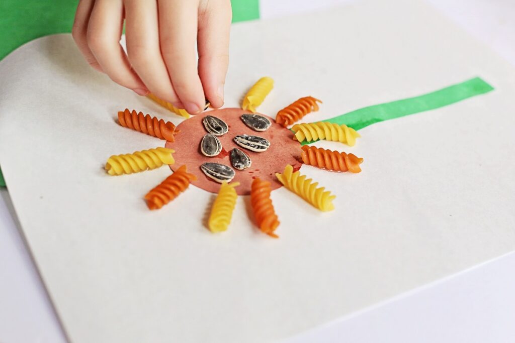 Close up view of child placing sunflower seeds in center of the project.