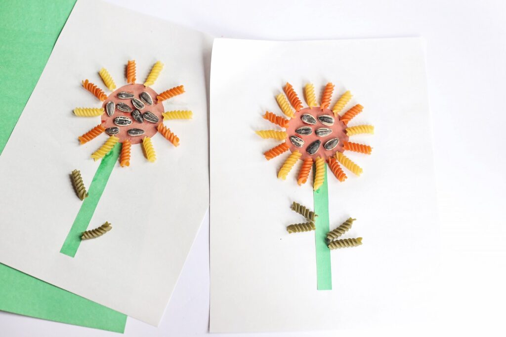 Two completed sunflower crafts made using pasta noodles and construction paper.