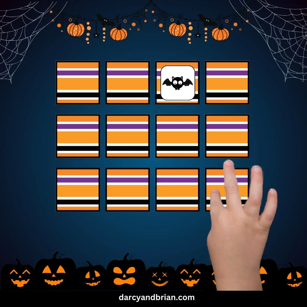 Cards laid down in a grid with the striped pattern in Halloween colors. One card flipped over to show a cute bat. Child's hand is selecting another card.