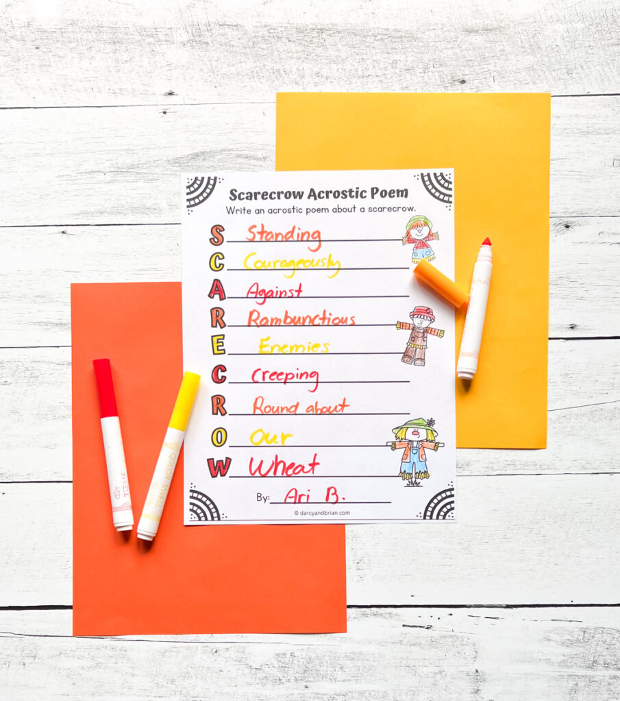 Acrostic poetry worksheet printed out and completed with words that start with each letter of scarecrow. The paper and markers are lying on top of orange and yellow paper.