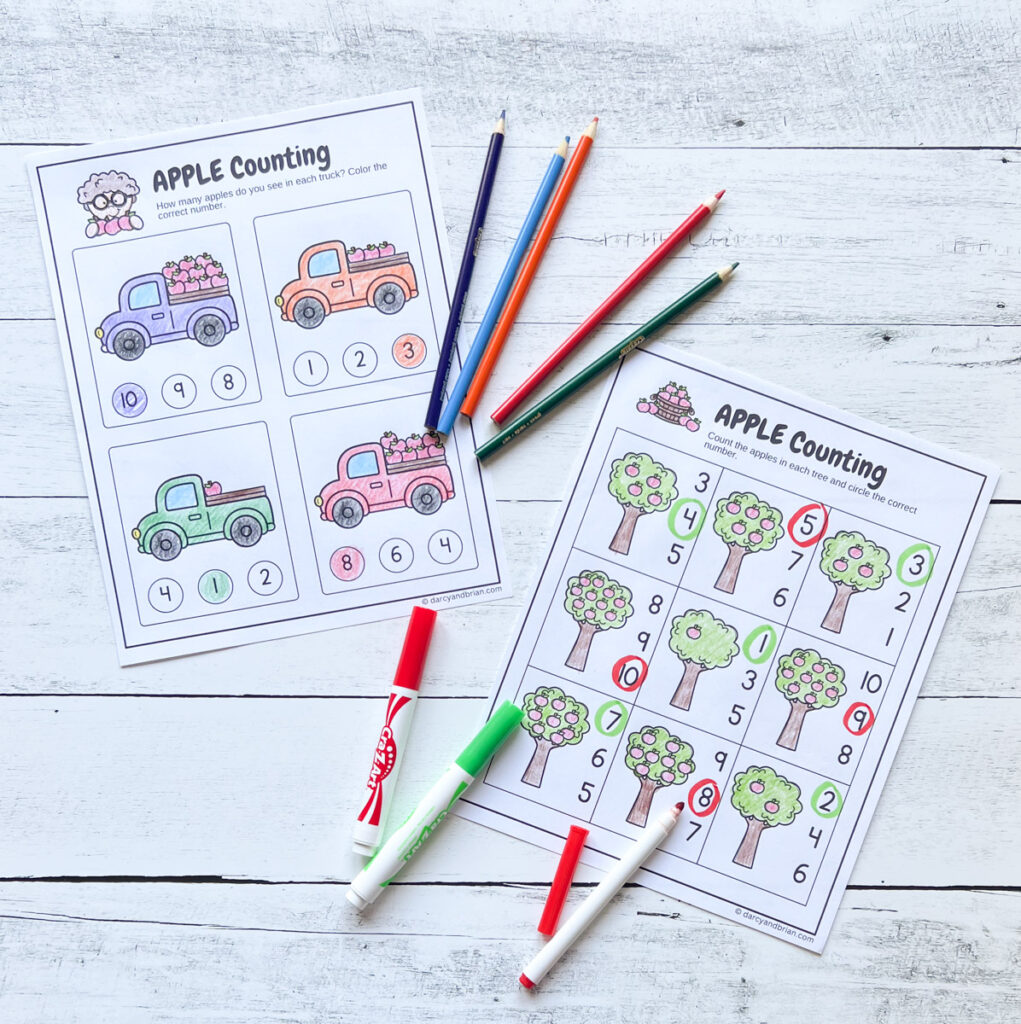 Two counting worksheets featuring trucks with apples in the back and apple trees. The images were colored in with markers and colored pencils and the answers filled in.