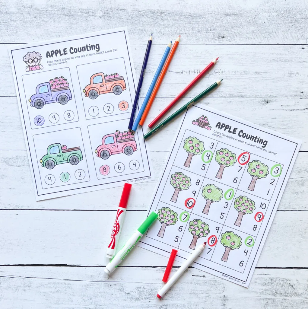 Two counting worksheets featuring trucks with apples in the back and apple trees. The images were colored in with markers and colored pencils and the answers filled in.