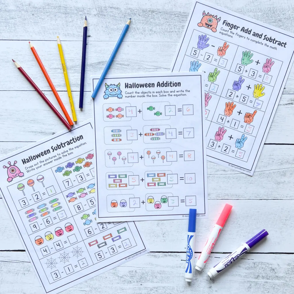 Three pages spread out on a table with Halloween visual math equations for kids to practice adding and subtracting.