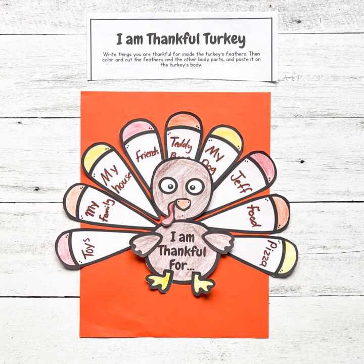 Completed I am Thankful Turkey Craft with words and colors placed in an orange construction paper with black and white wood background.