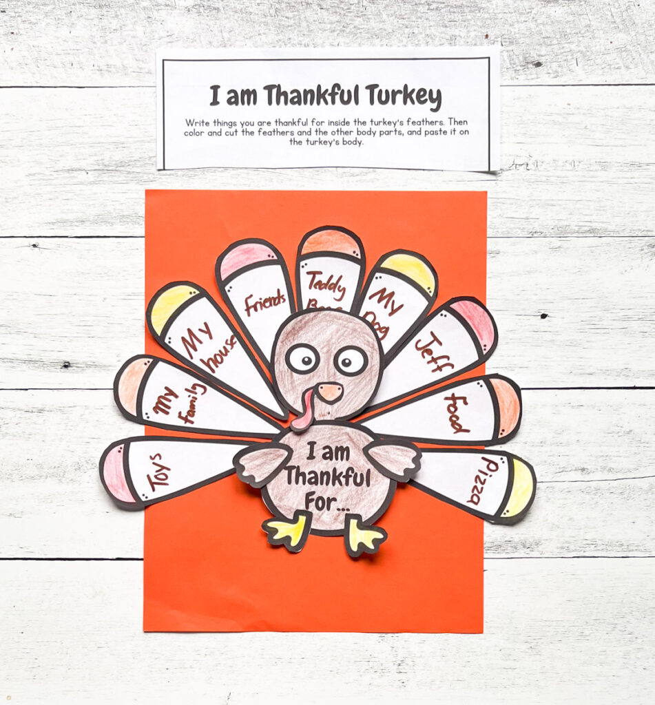 Completed I am Thankful Turkey Craft with words and colors placed in an orange construction paper with black and white wood background.