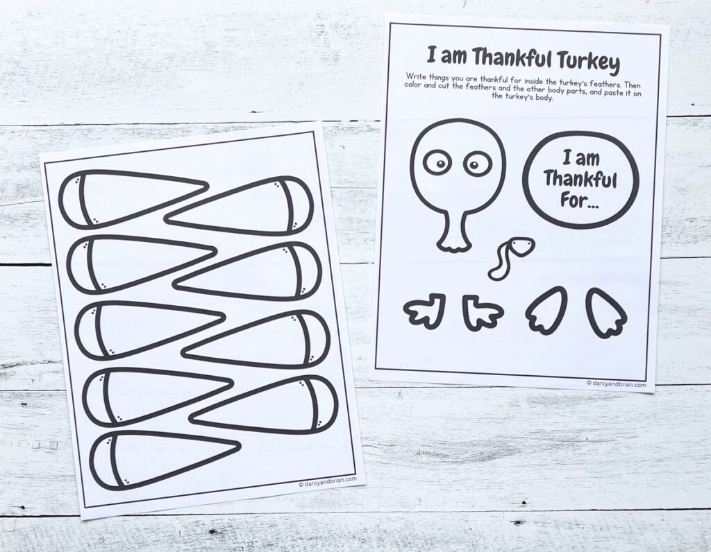 Two pages of I am Thankful worksheet printed out and ready to be colored and cut out. They are laying on a black and white wood background.