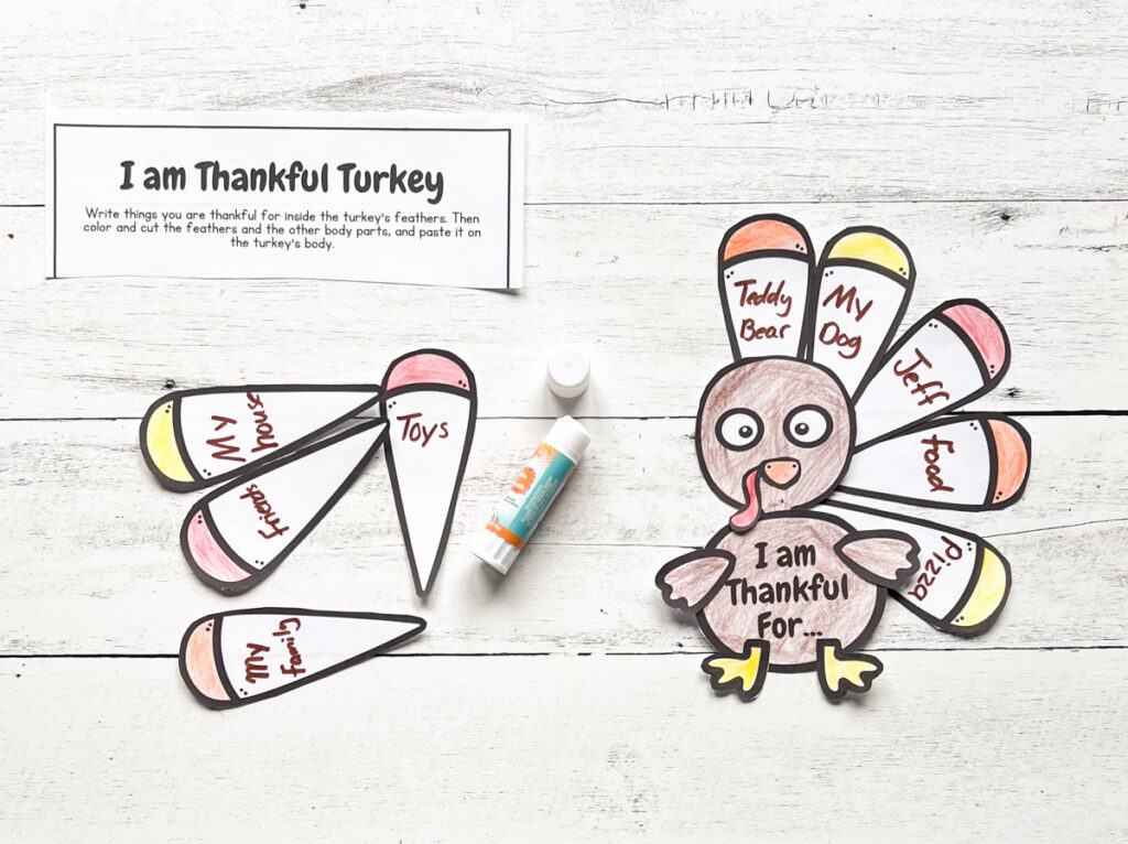 Gluing I am Thankful Turkey craft with words and colors as guide for kids placed in a black and white wood background.