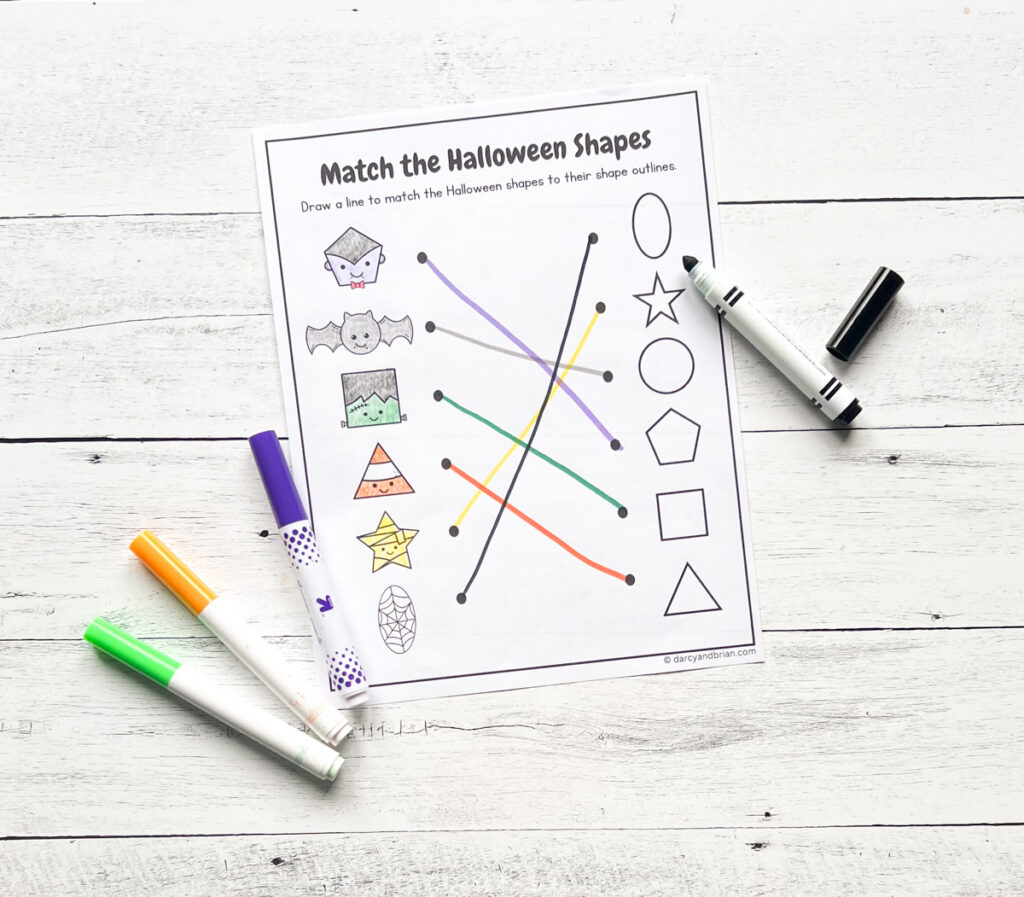 Completed worksheet with lines drawn between matching shapes. Markers lay next to the paper.