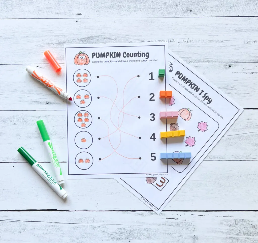 Lines drawn between groups of small pumpkins to the matching number on the worksheet. Math manipulatives and markers lay by the paper.