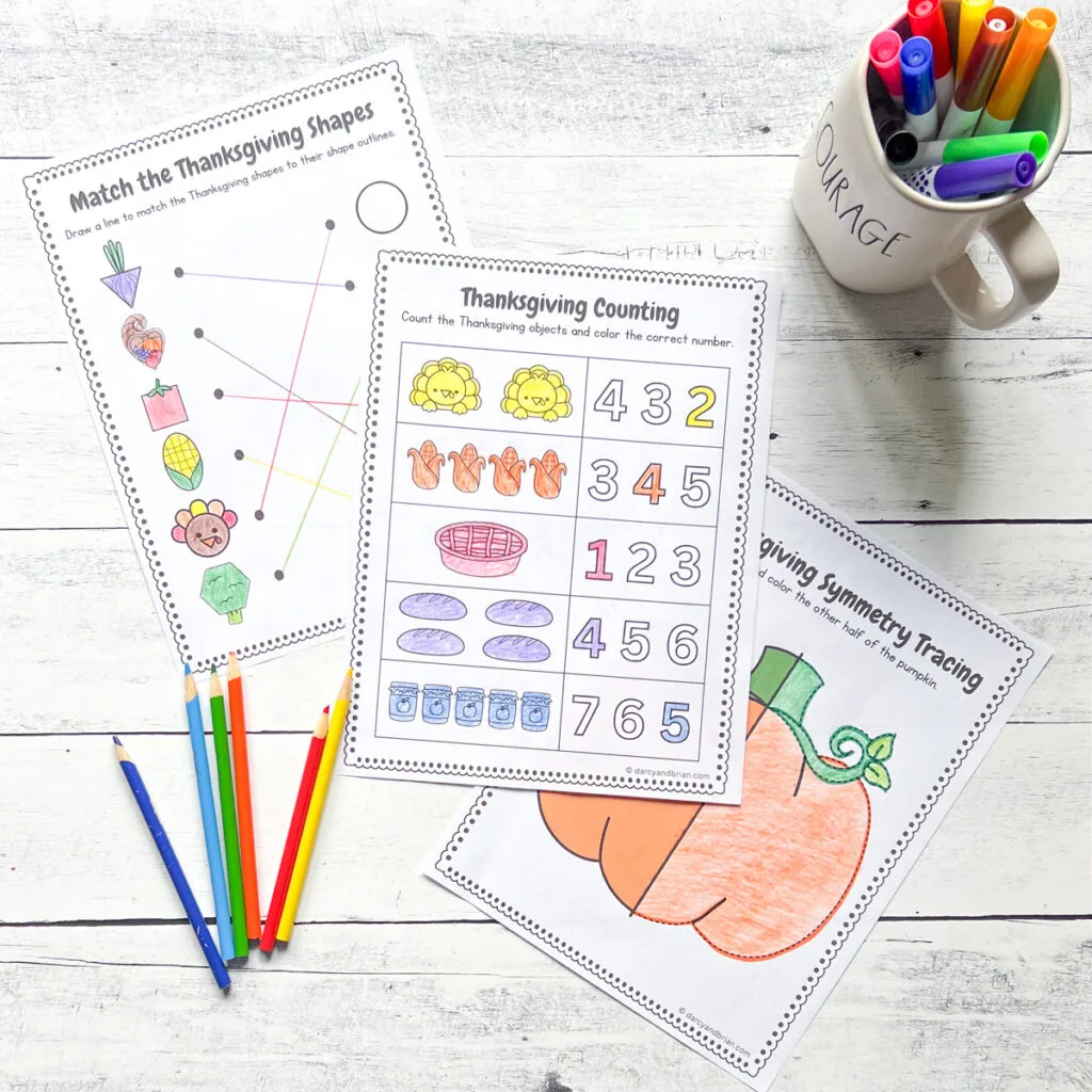 Three pages for Thanksgiving printables such as Matching, Counting, and Tracing along with the materials like color pencils and markers, all placed in a black and white wood background.