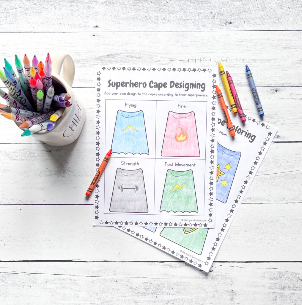 Completed worksheet with capes colored in with crayons. A mug of crayons sits next to the papers.