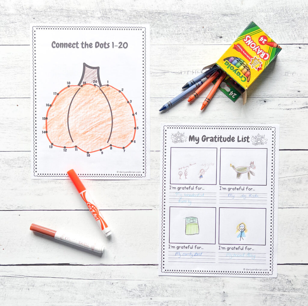 It has two pages of worksheets such as Connect the Dots 1-20 and My Gratitude List with the markers and crayons placed in black and white wood background.