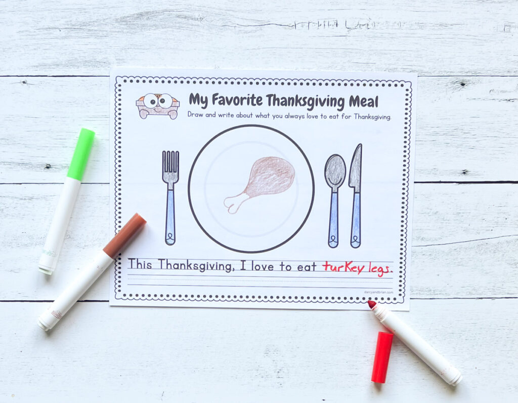 Worksheet with a place to draw different foods to create a Thanksgiving plate. This page has a turkey drumstick drawn on it. Markers lay around the paper.