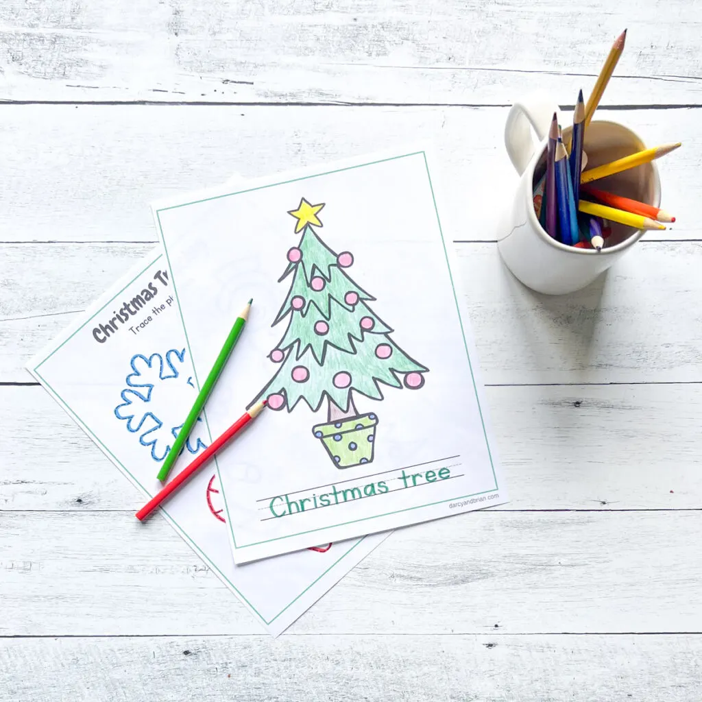 It has two pages of tracing activity with colors on the Christmas Tree, along with the color pencils placed in a black and white wood background.